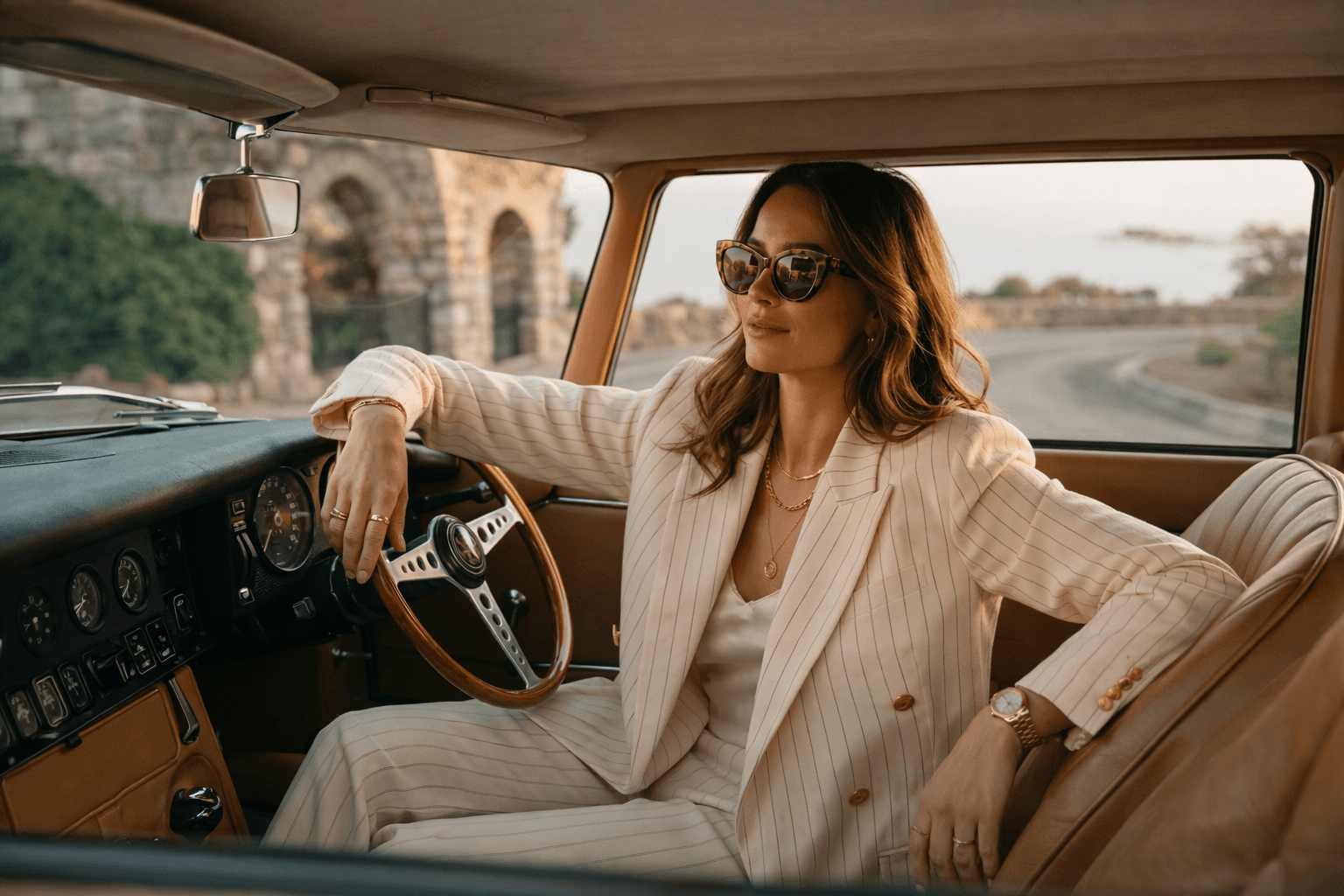 Modern Essentials — woman in pinstripe blazer driving a vintage car